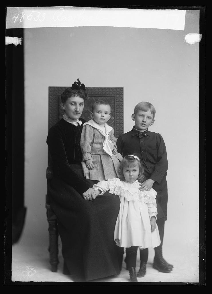 A mother seated with three young children gathered around her, photographed by C. M. Bell, identified only as "Rassbach."